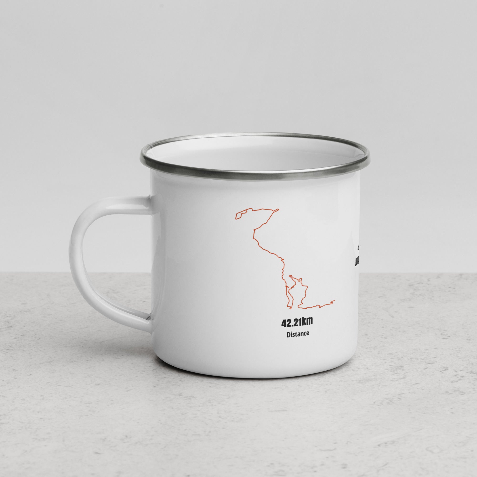 White enamel mug with orange custom Strava route print on a light gray surface