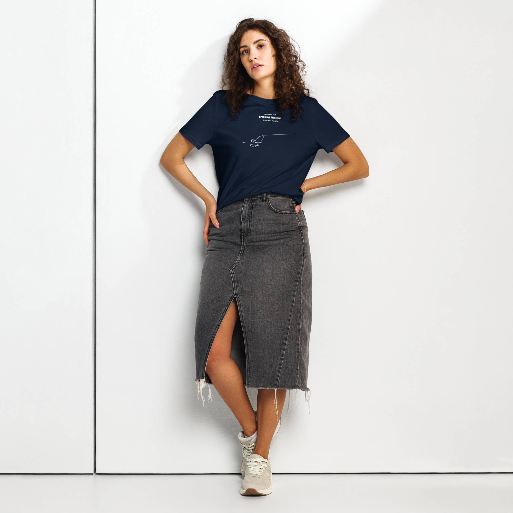 Woman wearing a navy t-shirt with custom Strava route print and gray denim skirt on a white background