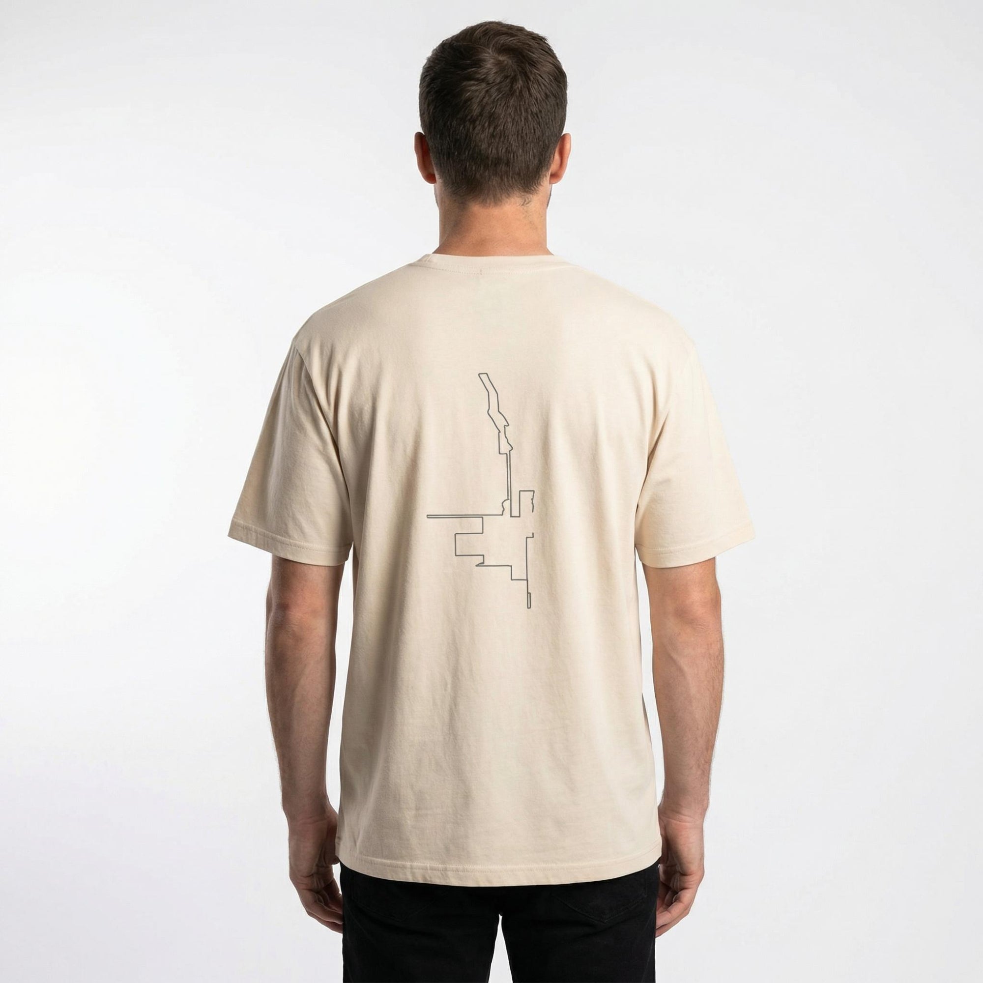 Man wearing a beige t-shirt with a custom Strava route print art design on the back, standing against a white background