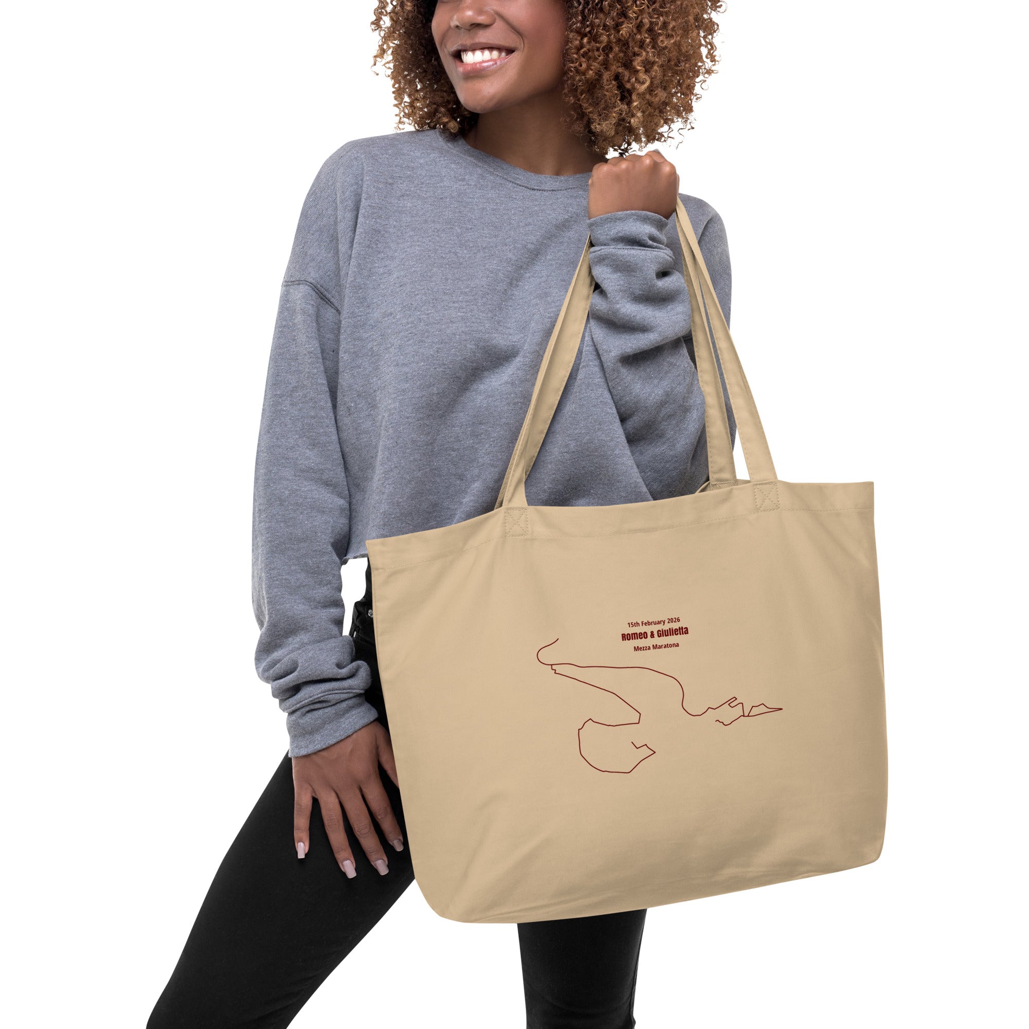 Woman holding a beige tote bag with a custom Strava route print art design on a white background