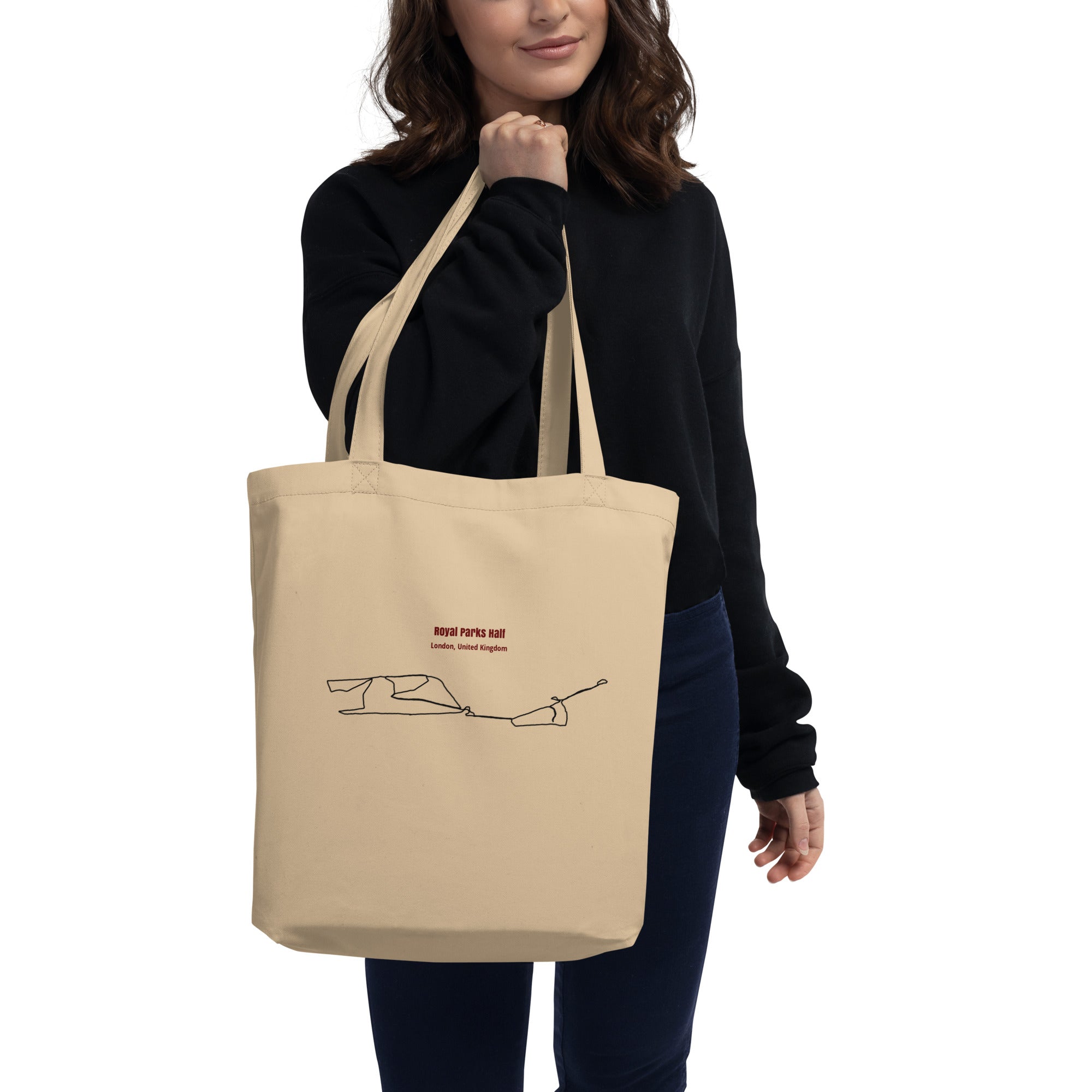 Person holding a beige tote bag with design on a white background