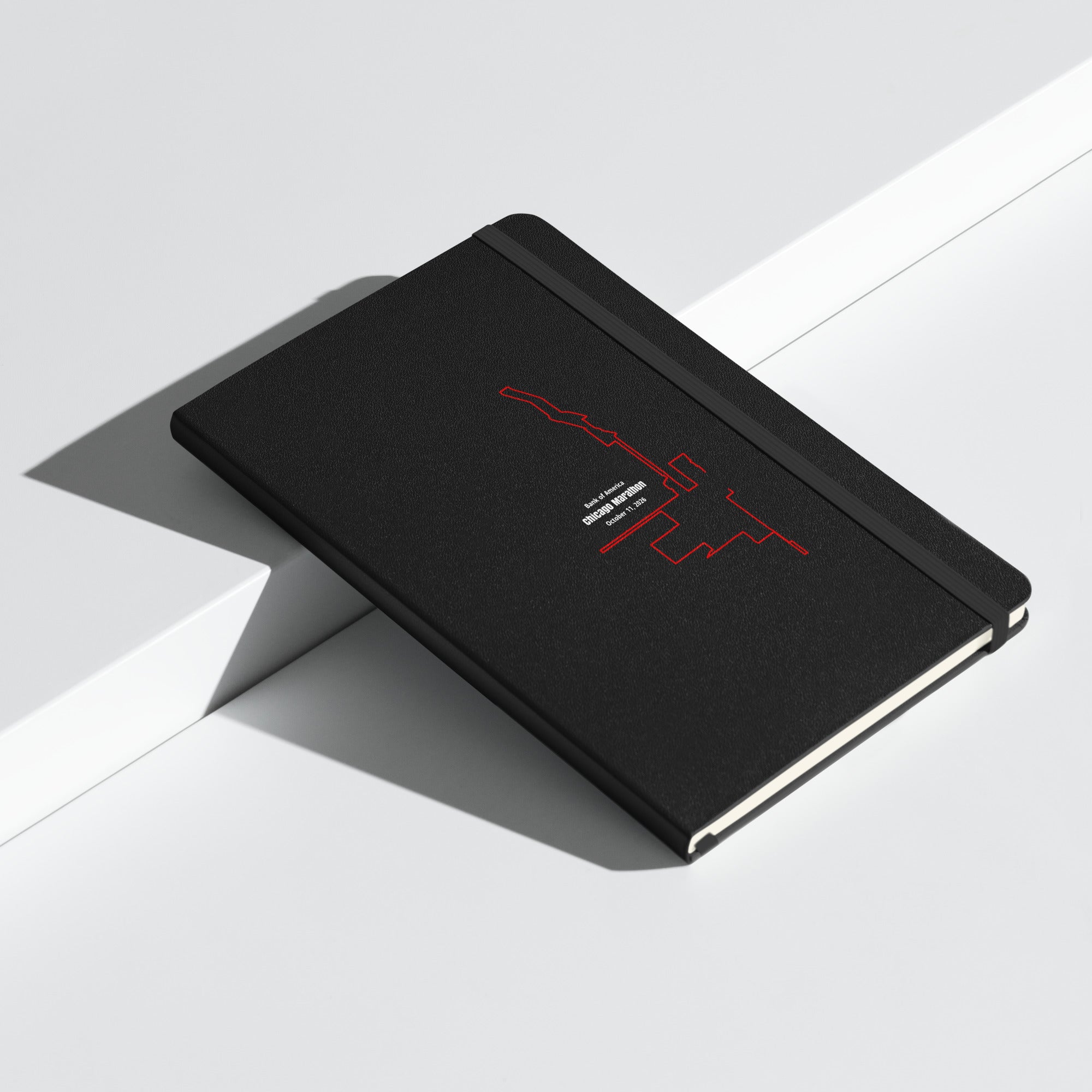 Black notebook with red custom Strava route print art design on a white surface