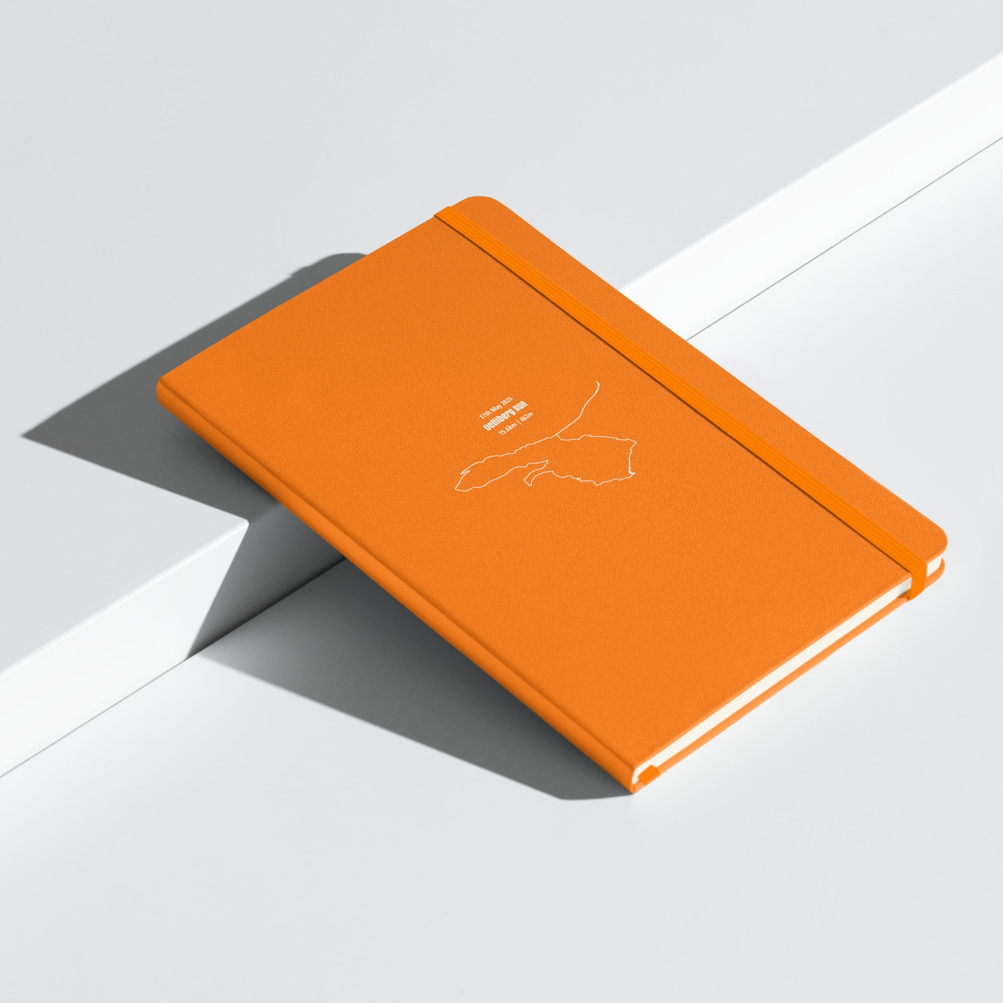 Orange notebook with custom Strava route print art design on a light gray background