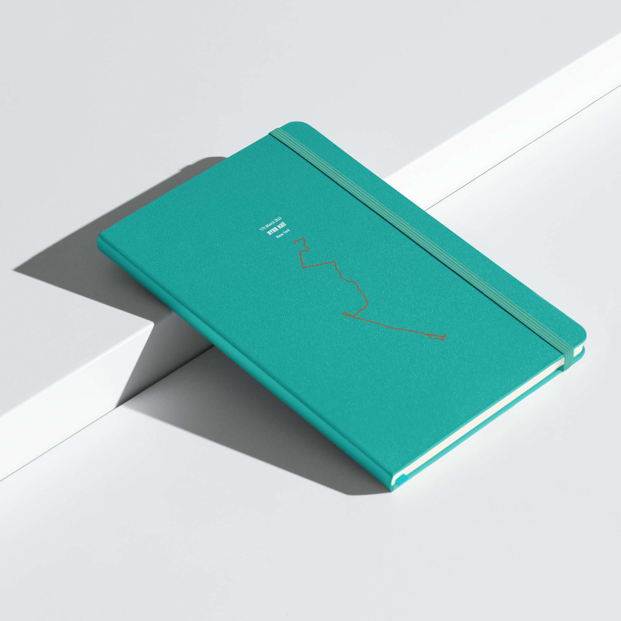 Green notebook with custom Strava route print art design on a light gray background