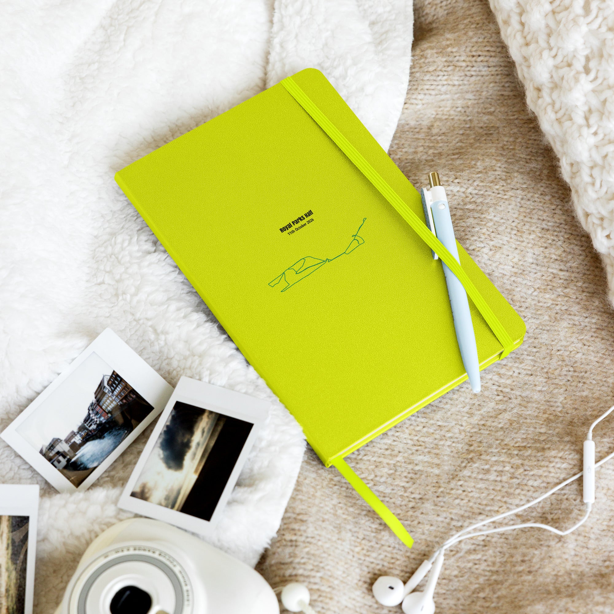 Green notebook with custom Strava route print art and a pen and photos on a textured surface