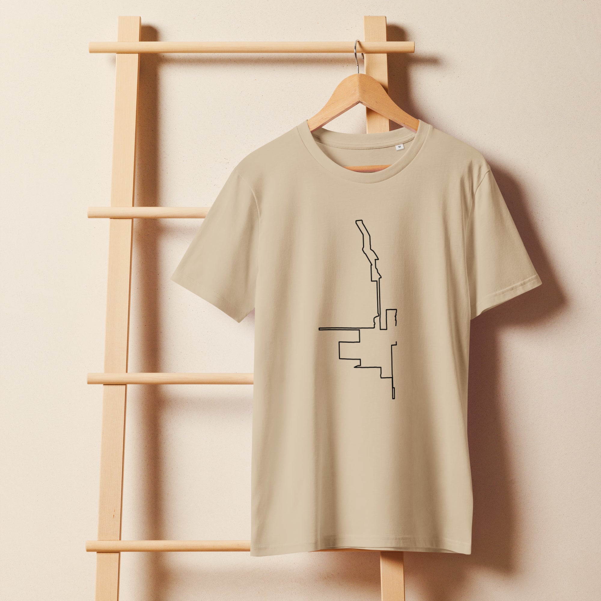 Beige t-shirt with a black custom Strava route print art design on a wooden hanger against a beige wall