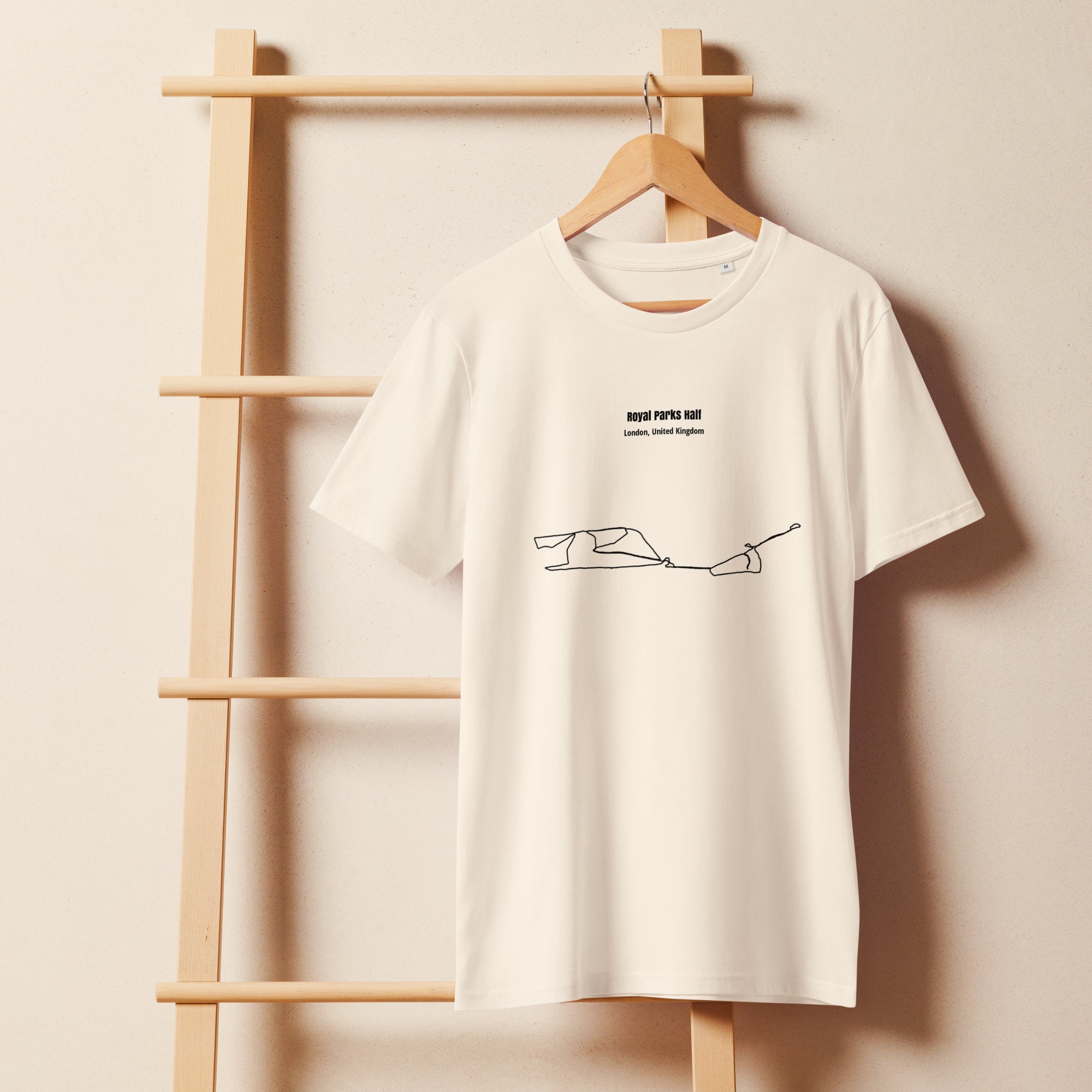 White t-shirt with custom Strava route print art design on a wooden hanger against a beige wall