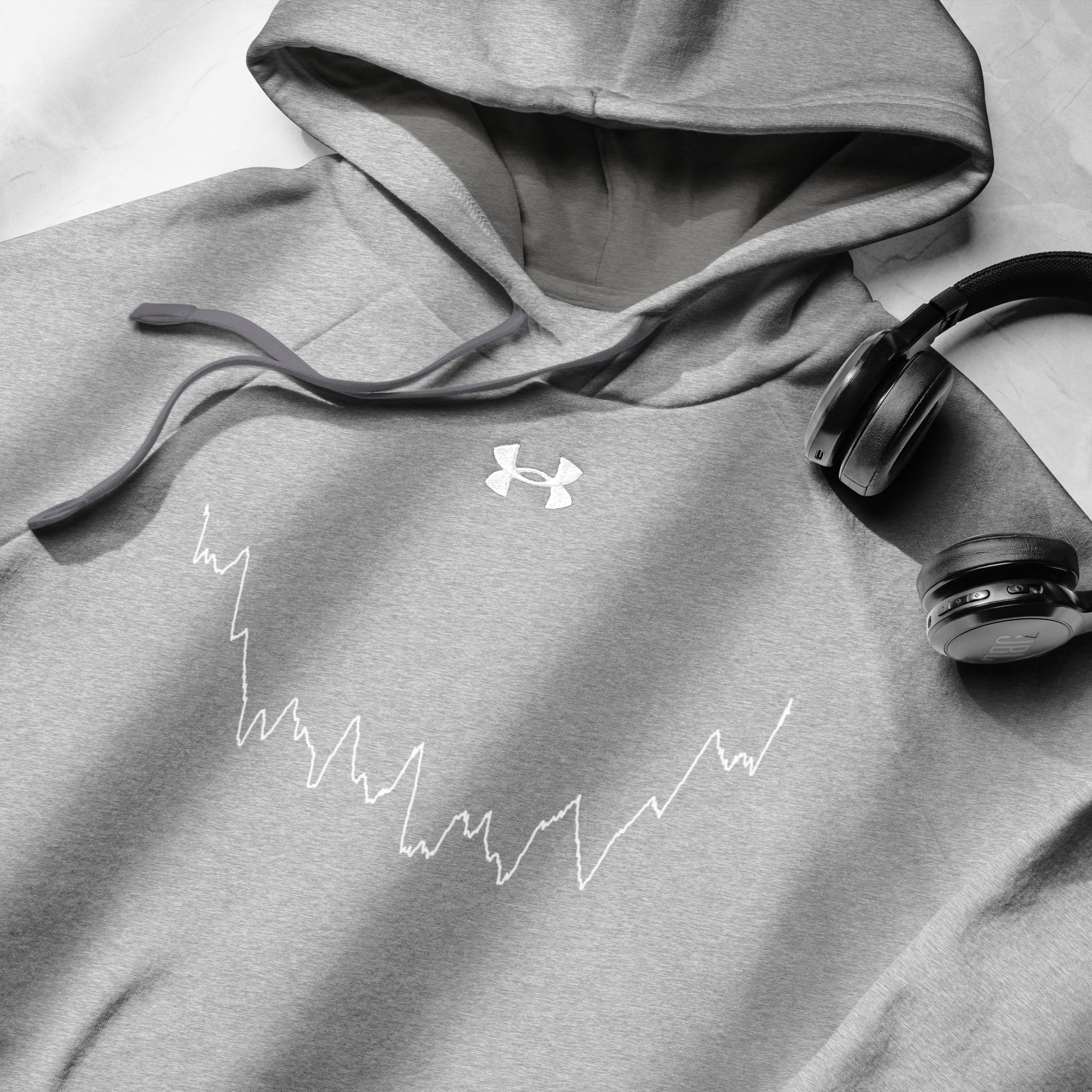 Gray hoodie with Under Armour logo and custom Strava route print design, paired with headphones