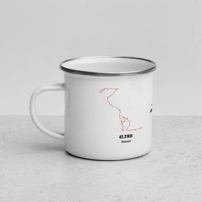 White enamel mug with orange custom Strava route print on a light gray surface