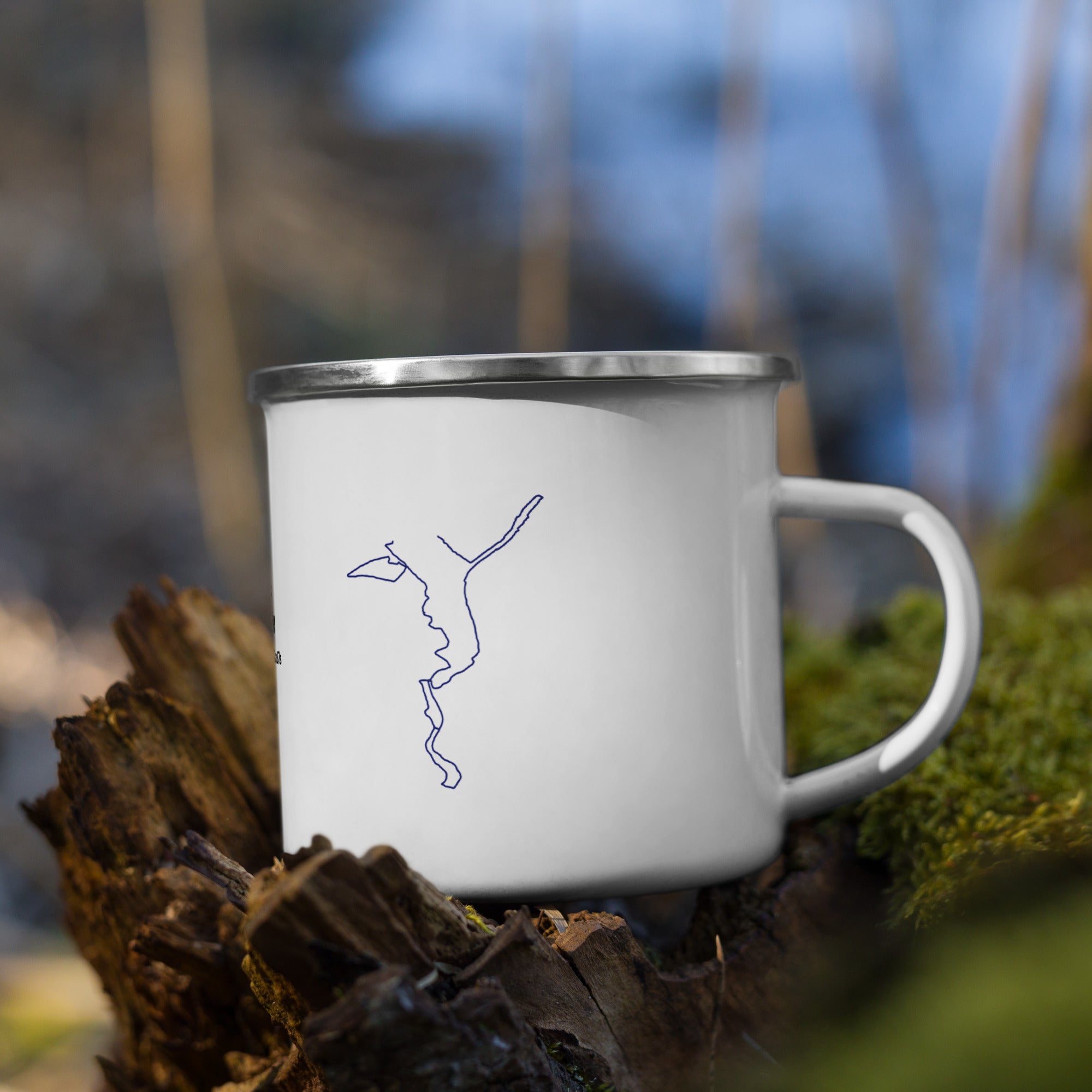 White mug with a blue custom Strava route print drawing on a log with a blurred natural background