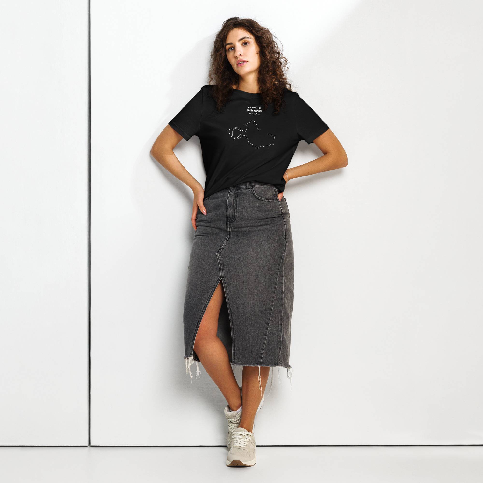 Woman wearing a black t-shirt with custom Strava route print and gray denim skirt on a white background