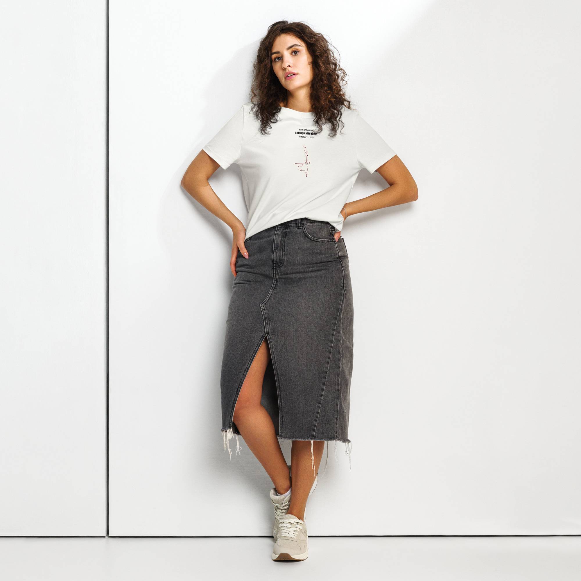 Woman wearing a white t-shirt with custom Strava route print and gray denim skirt on a white background