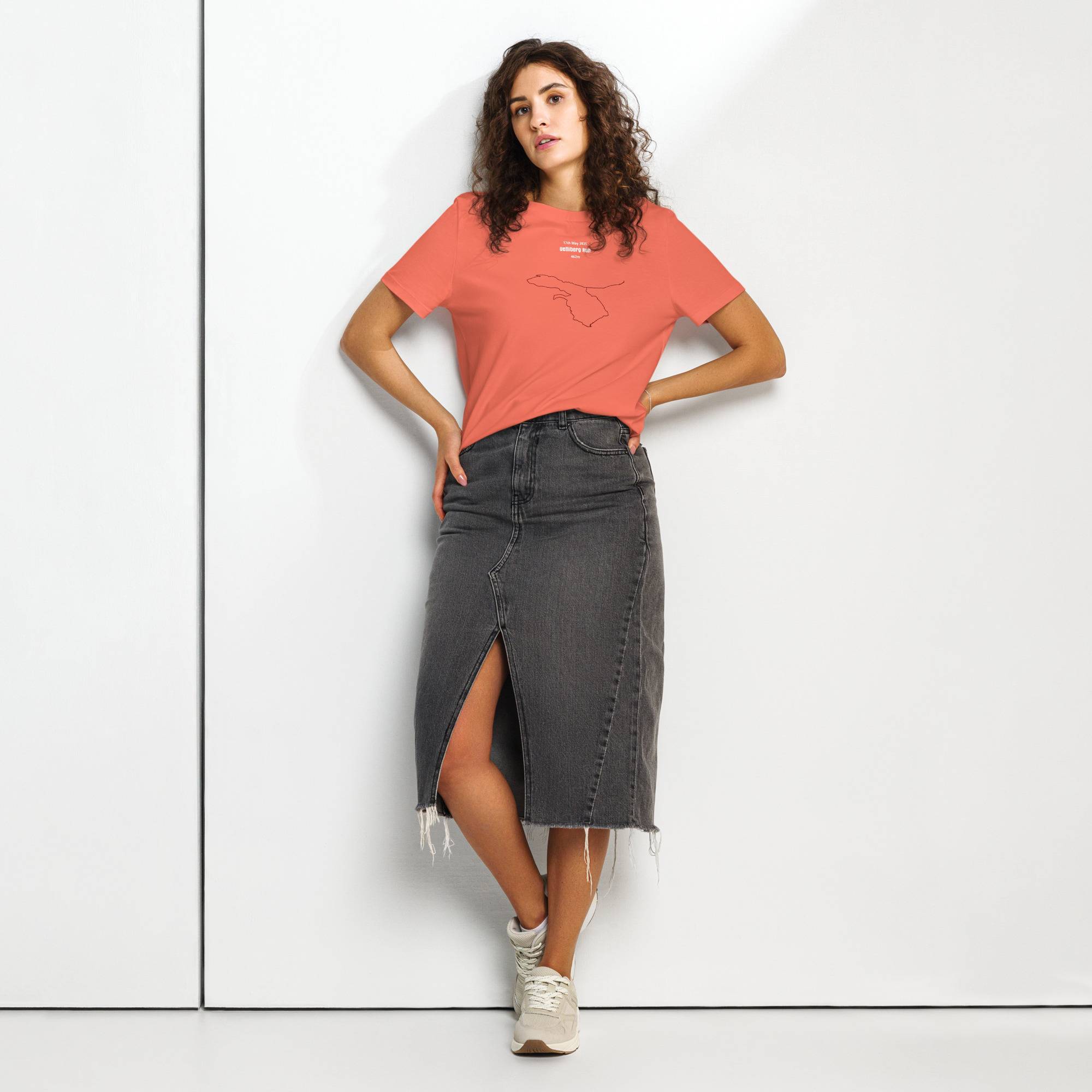 Woman wearing a coral t-shirt with custom Strava route print and black denim skirt on a white background