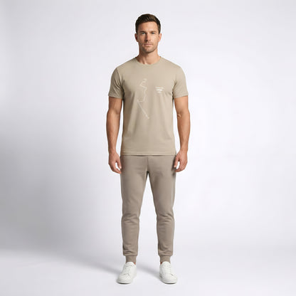 Man wearing a brown t-shirt with custom Strava route print art and trousers on a white background