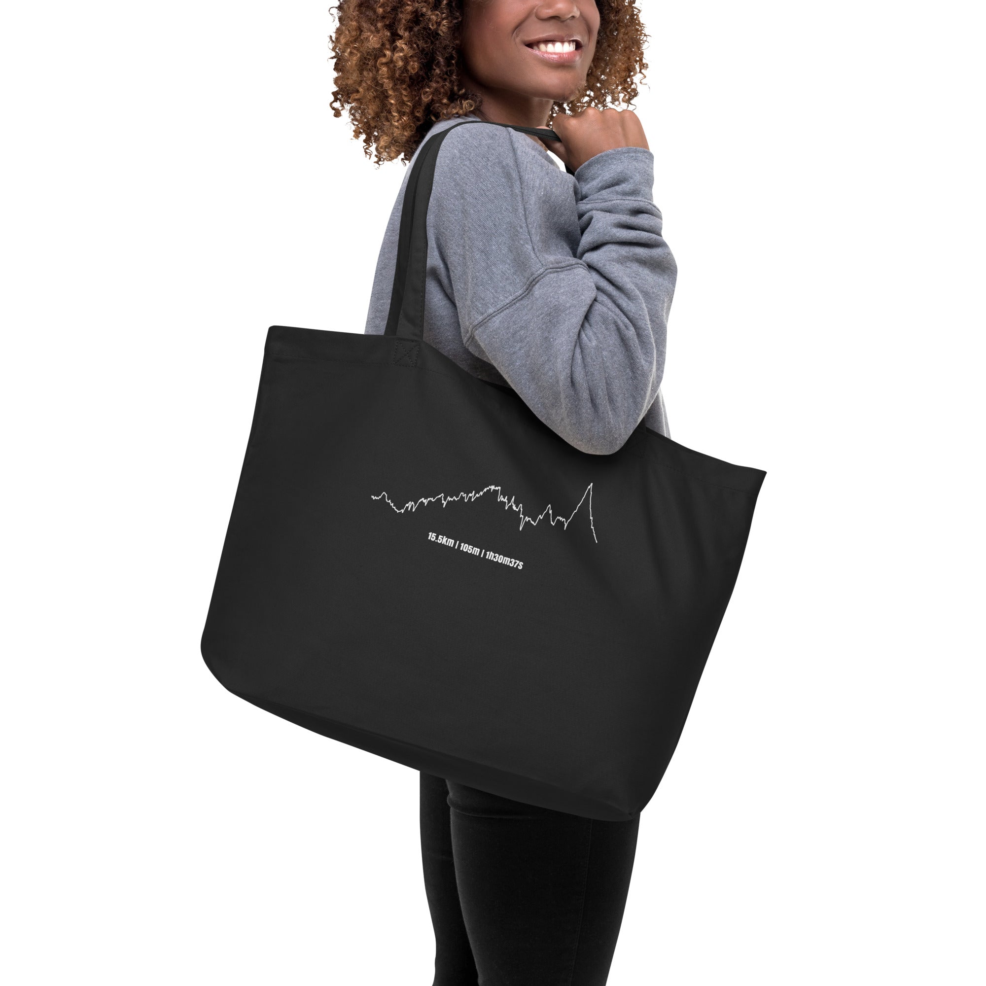 Person holding a black tote bag with a white custom Strava route print art design on a white background