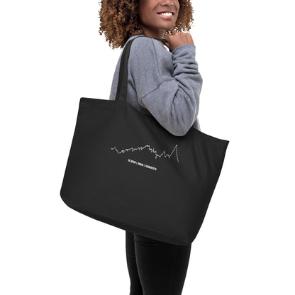 Person holding a black tote bag with a white custom Strava route print art design on a white background