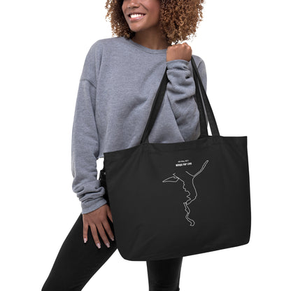 Woman holding a black tote bag with a custom Strava route print art design on a white background
