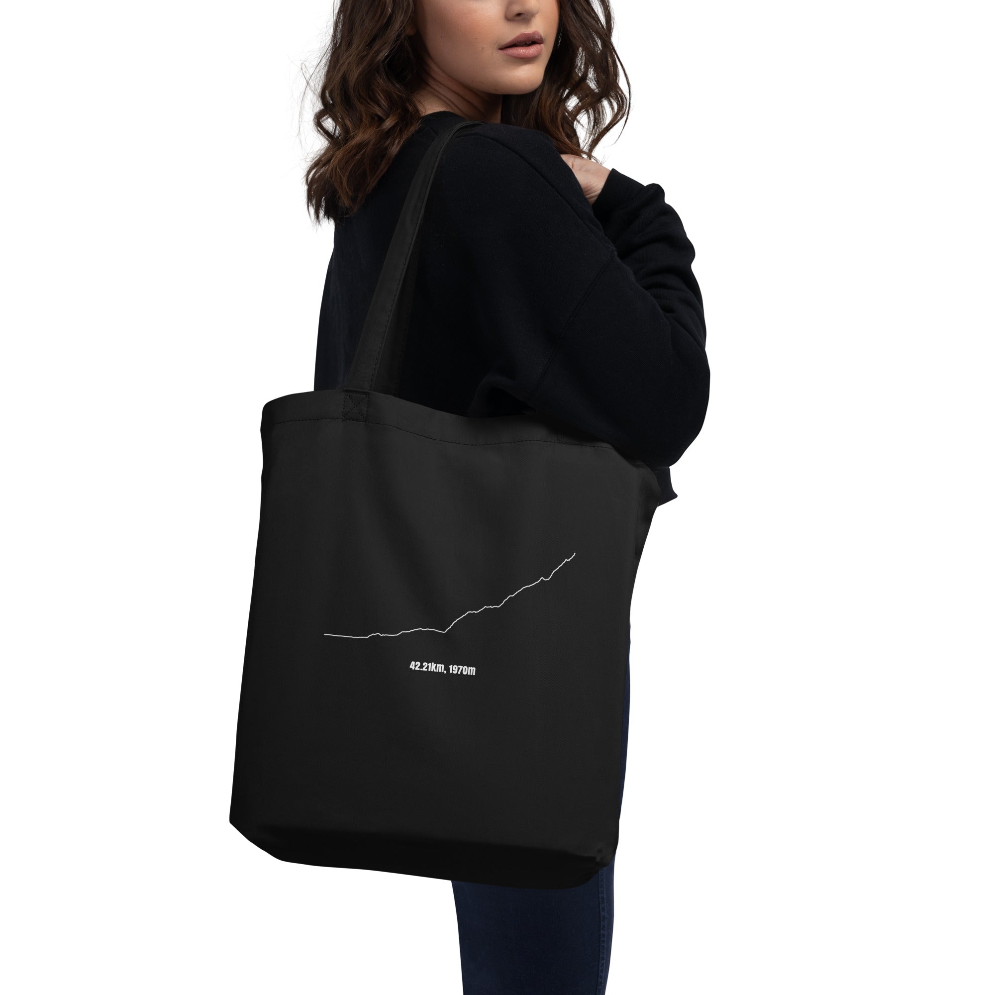 Person holding a black tote bag with a white custom Strava route print art design on a white background