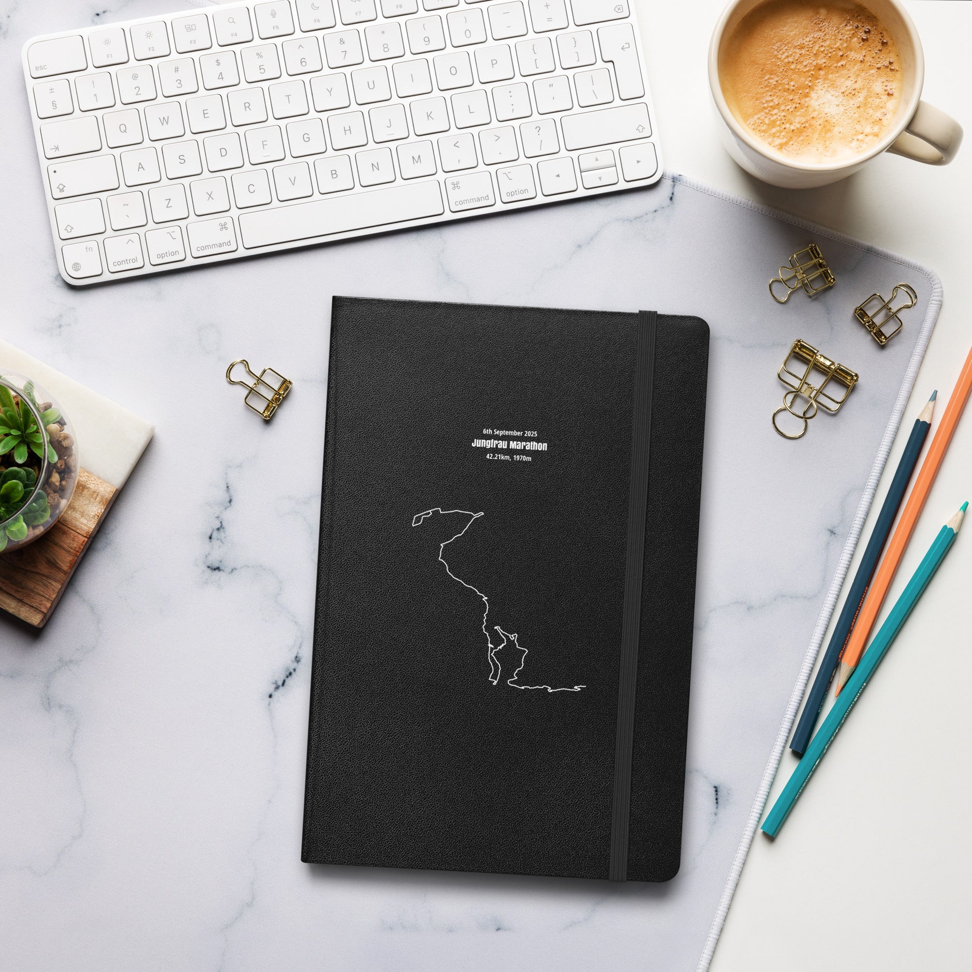 Black notebook with custom Strava route print art design on a marble desk with office supplies