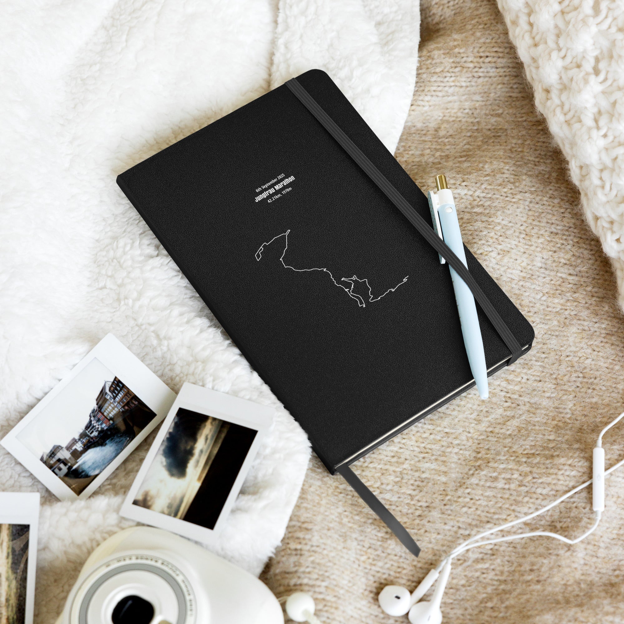 Black notebook with custom Strava route print art design on a textured surface with photos and earphones
