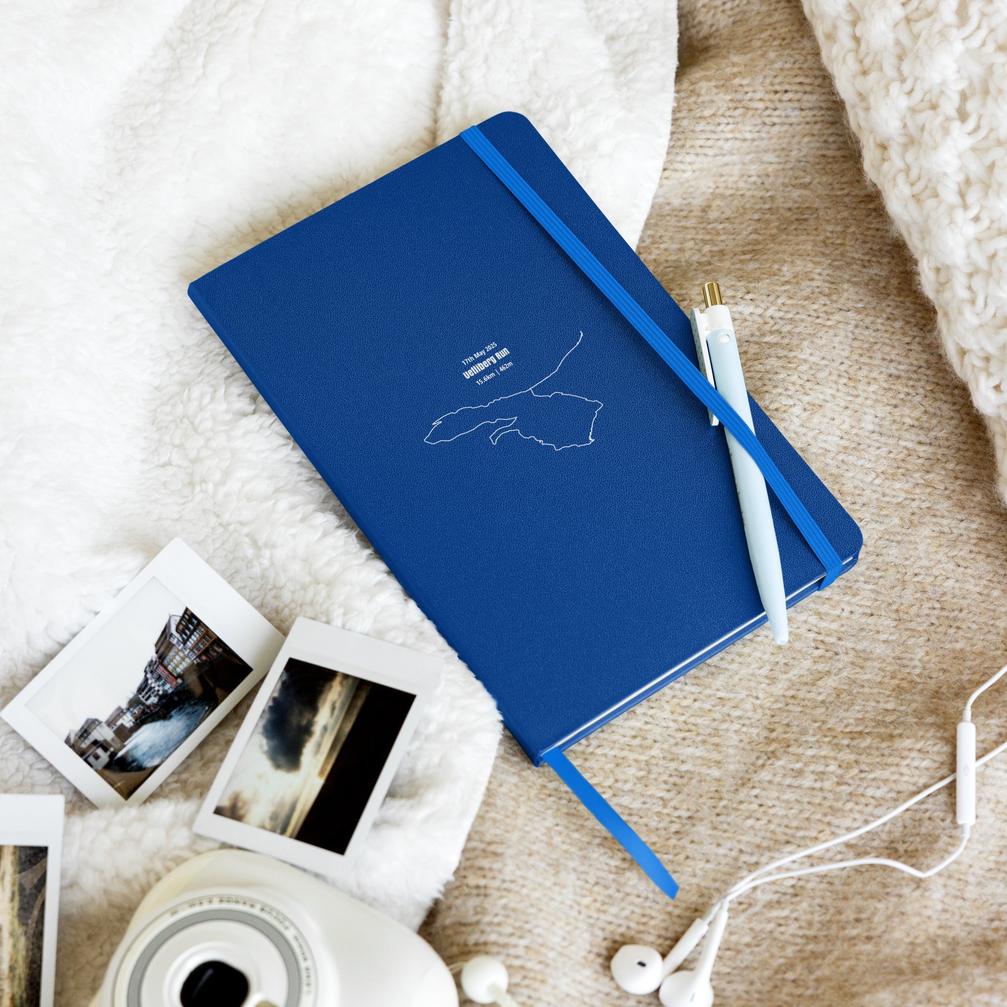 Blue notebook with custom Strava route print art and photos on a textured surface