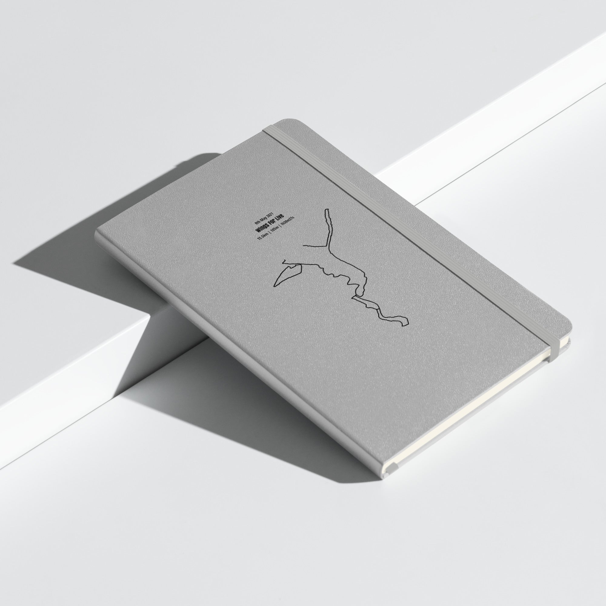 Gray notebook with custom Strava route print art design on a light gray background