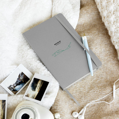 Gray notebook with custom Strava route print art on a textured surface with instant photos and earphones