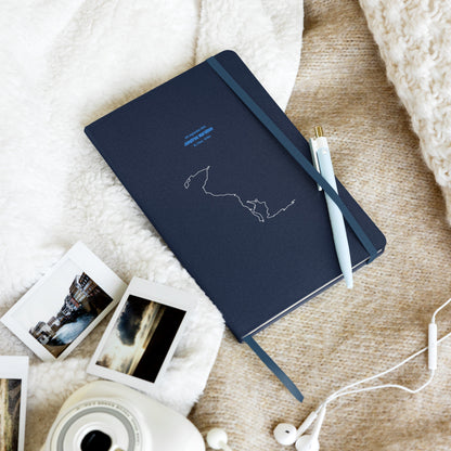 Dark blue notebook with custom Strava route print art design on a textured surface with photos and earphones