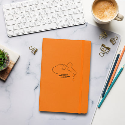 Orange notebook with custom Strava route print art design on a marble desk with office supplies and a cup of coffee