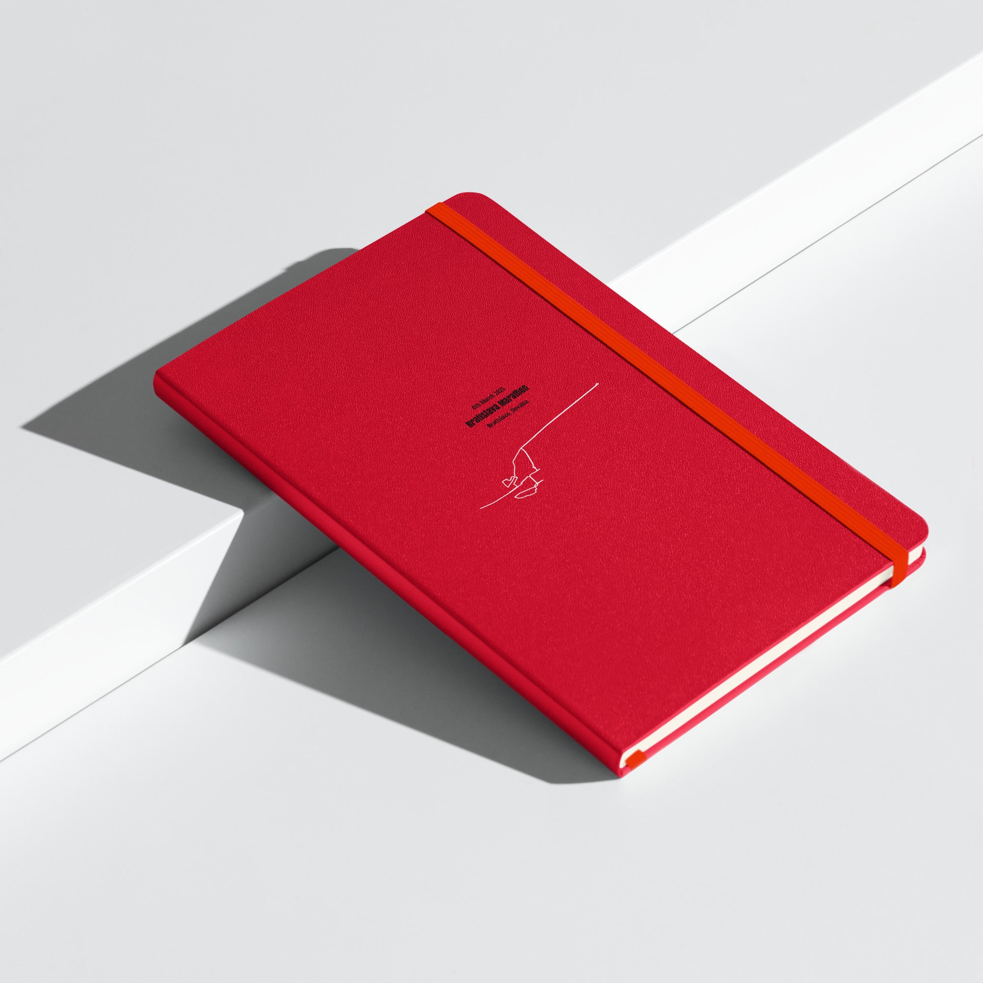 Red notebook with a whitecustom Strava route print art on a light gray background