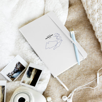 Notebook with custom Strava route print art and a pen, photo album, and photos on a textured surface