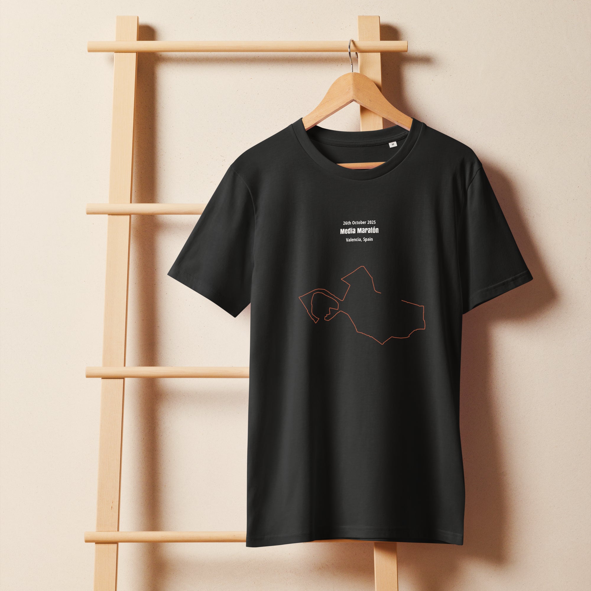 Black t-shirt with a custom Strava route print art design on a wooden hanger against a beige wall