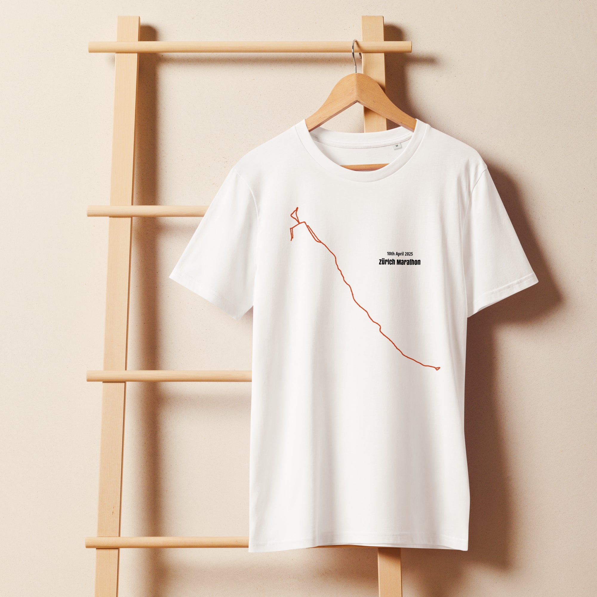 White t-shirt with a custom Strava route print art design on a wooden hanger against a beige wall