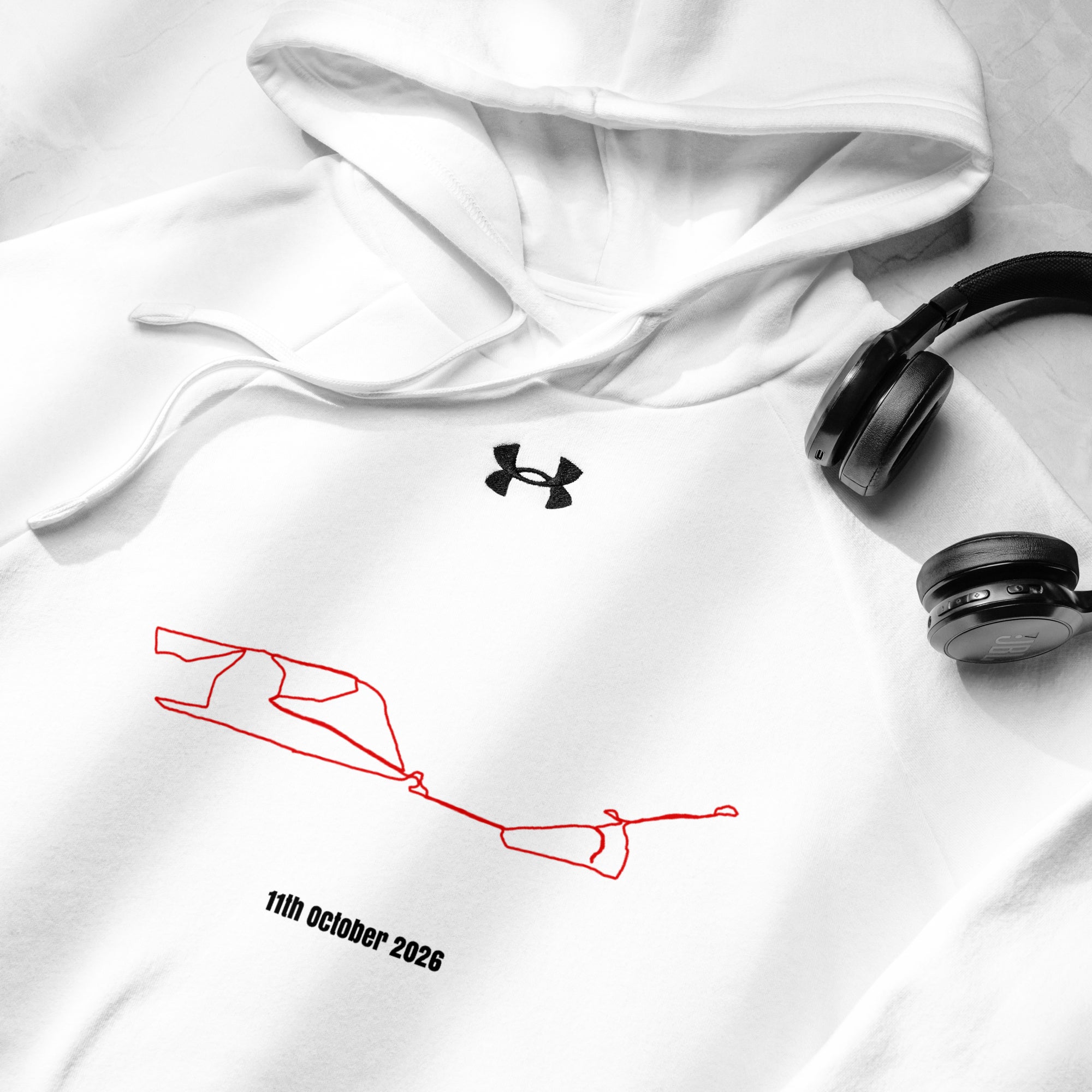 White hoodie with red custom Strava route print design and black Under Armour logo, accompanied by black headphones