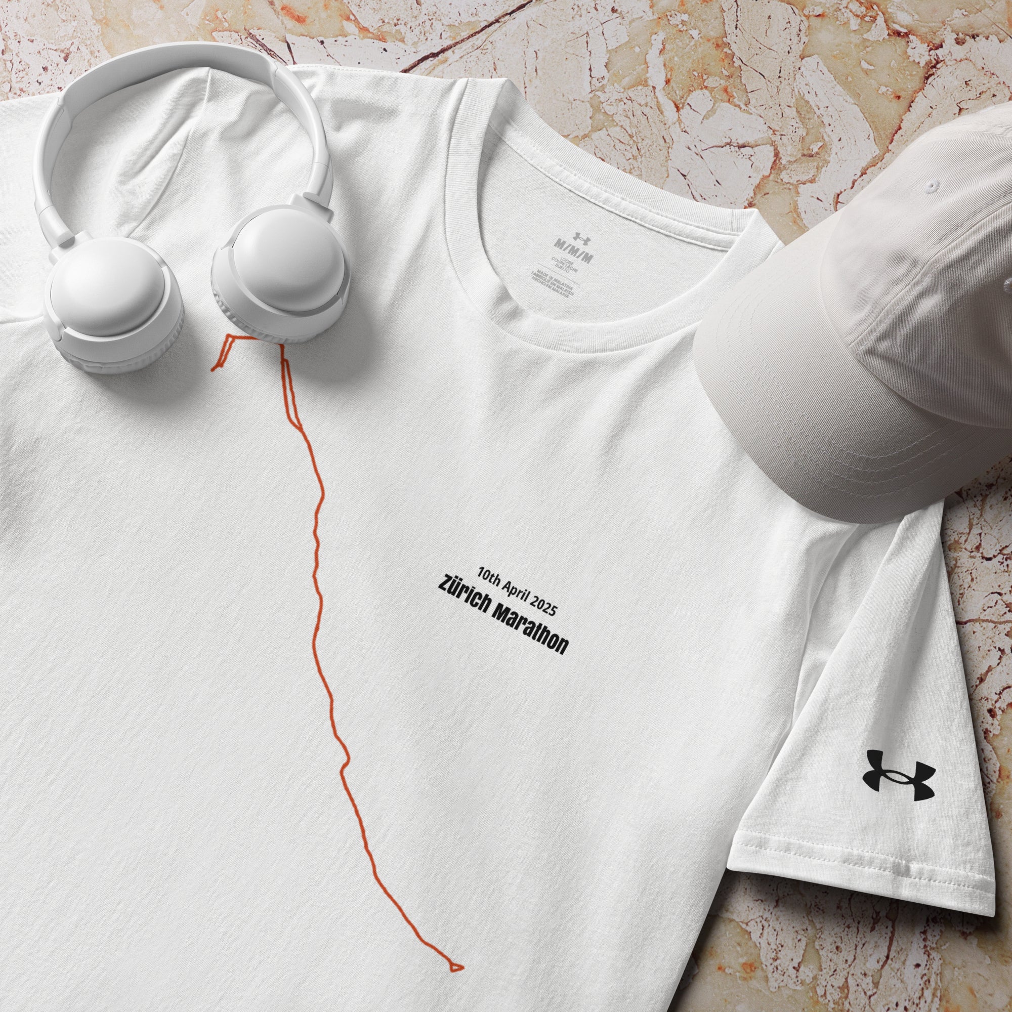 White t-shirt with marathon custom Strava route print design, cap, and headphones on a marble surface